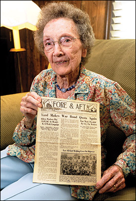 Johnson holds an old company newspaper with a photo of her with a welding crew.
