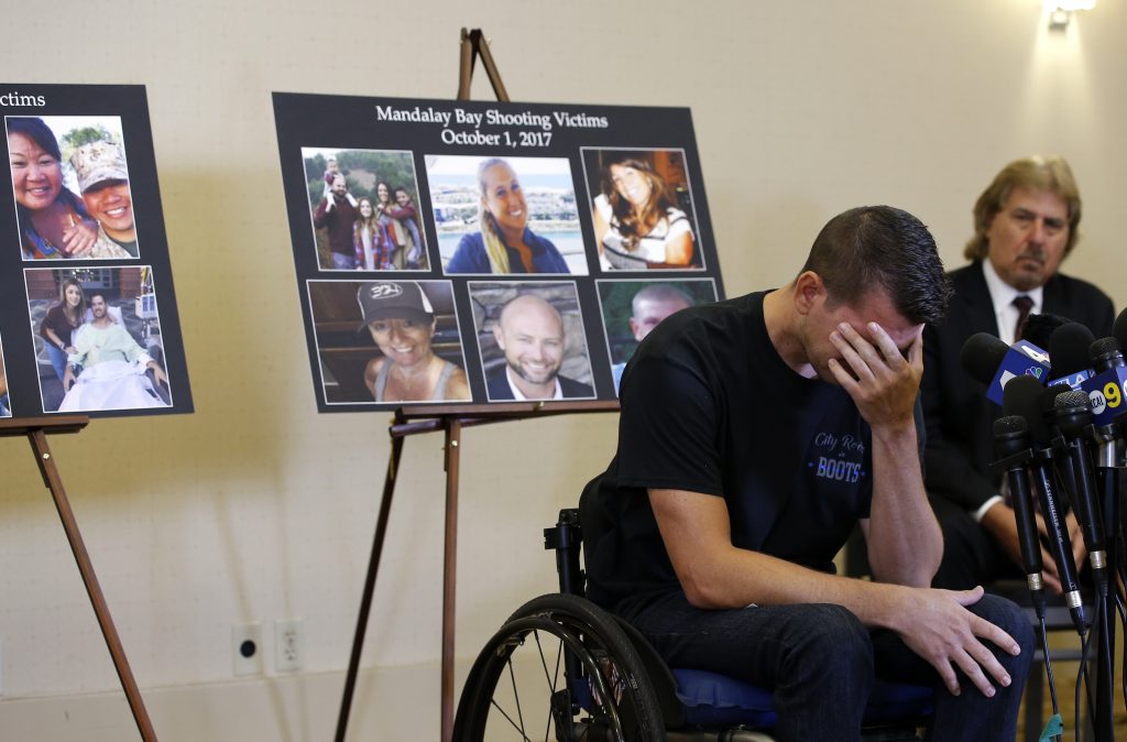 Jason McMillan, 36, of Riverside, a Riverside County Sheriff's deputy who was shot and paralyzed in the Oct, 1, 2017, Las Vegas shooting, reacts as he talks about that evening and is upset MGM's decision, during a personal account brought together by attorneys at a news conference in Newport Beach, Calif., Monday, July 23, 2018. Behind McMillan are images of the shooting victims of the October 1, 2017 shooting. Victims of the fatal mass shooting at a Las Vegas country music festival are outraged they are being sued by MGM, which owns the hotel where the gunman opened fire. (AP Photo/Alex Gallardo)