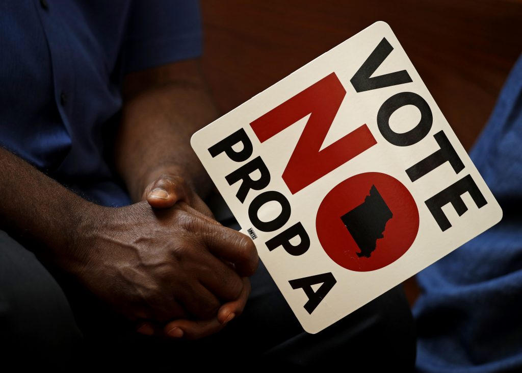 FILE - In this Tuesday, July 31, 2018, file photo, people opposing Proposition A listen to a speaker during a rally in Kansas City, Mo. Missouri votes Tuesday, Aug. 7 on a so-called right-to-work law, a voter referendum seeking to ban compulsory union fees in all private-sector workplaces. (AP Photo/Charlie Riedel, File)