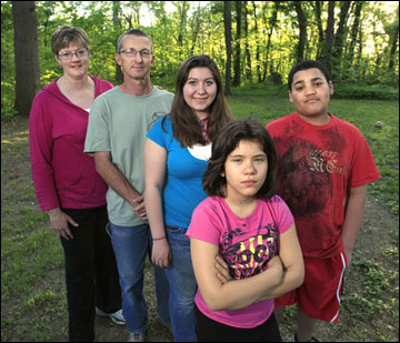 Mary and Joe Thompson stand with their children -- Sarah (center), Andrew and Emily -- at their home in Overland Park, Kan., recently. Mary Thompson was sure the health care law would finally let them get Emily on the family’s health insurance. Insurers had repeatedly rejected Emily due to a birth defect now largely overcome. The law requires insurers to accept children regardless of pre-existing health problems, a safeguard that will extend to people of all ages in 2014. But because Emily’s father is self-employed and the family buys its own coverage, things didn’t work out as expected. A year after President Barack Obama signed his health care overhaul, the law remains so divisive that Americans can’t even agree what to call it. (AP File Photo/Charlie Riedel)