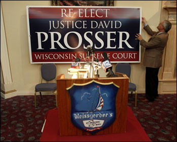 Waukesha County Executive Dan Vrakas hangs a sign behind a podium for Justice David Prosser at the Seven Seas Restaurant on April 5 in Waukesha. Prosser's camp is declaring victory after a close election. (AP Photo/Darren Hauck)