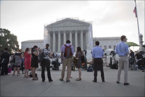 People wait outside the Supreme Court in Washington as key decisions are expected to be announced Monday, June 24, 2013. At the end of the court's term, several major cases are still outstanding that could have widespread political impact on same-sex marriage, voting rights, and affirmative action. (AP Photo/J. Scott Applewhite)