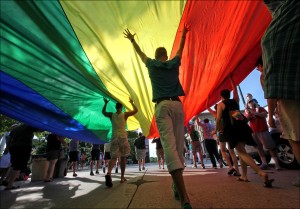 Supporters of a U.S. Supreme Court ruling which overturns the federal Defense of Marriage Act (DOMA) carry a large rainbow flag during a parade around the Wisconsin State Capitol in Madison, Wis. Wednesday, June 26, 2013. The decision grants federal benefits to married couples in states that recognize same-sex marriage, although Wisconsin is not one of them. (AP Photo/Wisconsin State Journal, John Hart)