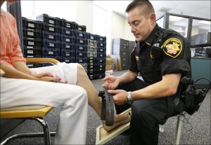 Deputy Edward Schinkal attaches an electronic monitoring unit to a woman who was sentenced to home incarceration, in Cincinnati. At least 100,000 sex offenders, parolees and people free on bail or probation now wear ankle bracelets that can sound an alarm if they leave home without permission, fail to show up for work or linger near a playground or school. (AP Photo/The Cincinnati Enquirer, Carrie Cochran, File)