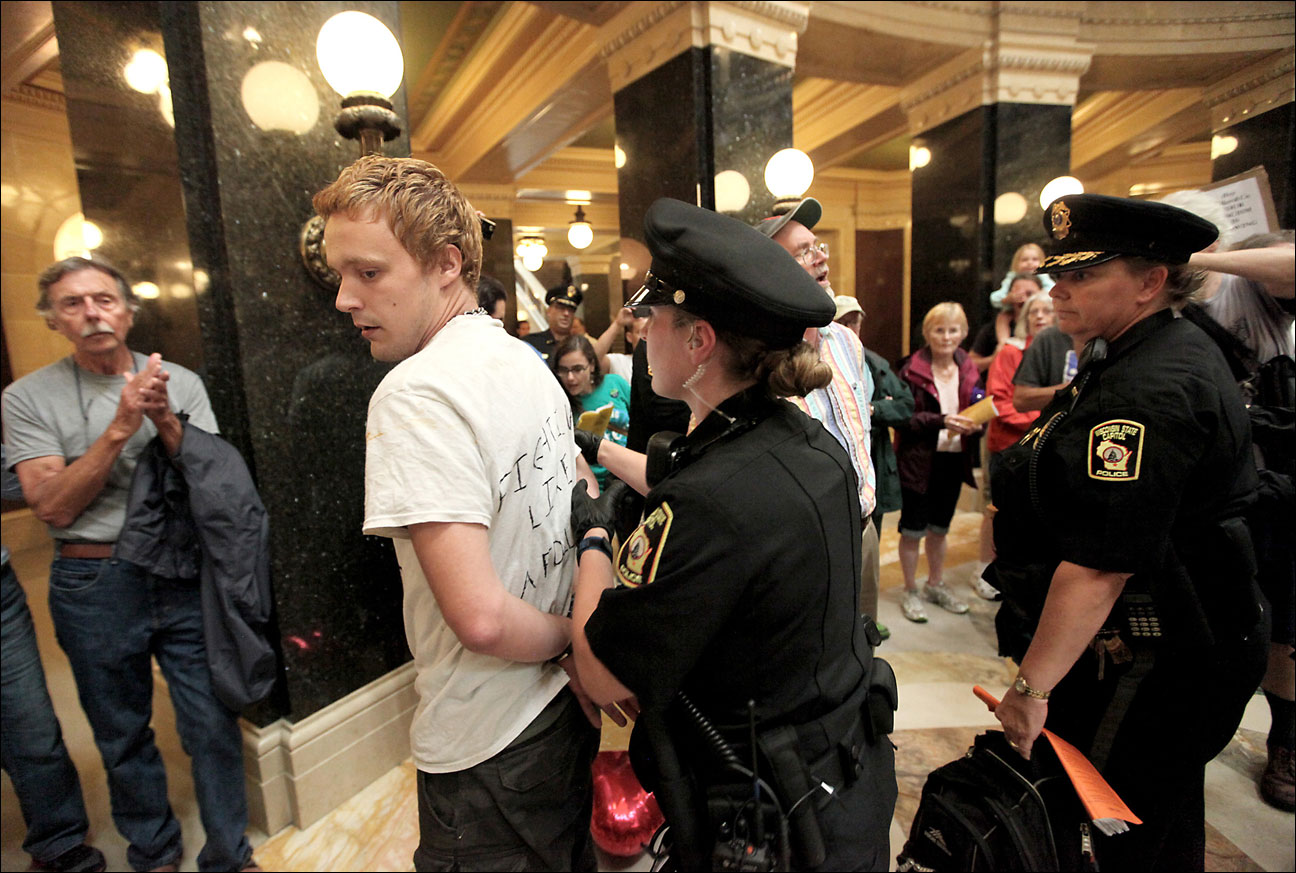 An opponent of Wisconsin Governor Scott Walker's administration is arrested by Wisconsin Capitol Police Department officers during an assembly in the rotunda of the state Capitol building Friday, July 26, 2013. For the third consecutive day, capitol police issued citations to protesters for gathering in the building without a permit. (AP Photo/Wisconsin State Journal, John Hart)