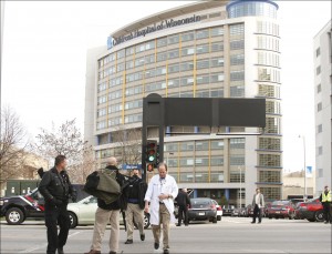 A doctor is lead across the street by police officers during a lockdown evacuation outside the Children's Hospital of Wisconsin on Thursday, Nov. 14, 2013 in Wauwatosa, Wis. Police officers shot and wounded a man inside Children's Hospital of Wisconsin where they had gone to arrest him on a felony warrant, according to Milwaukee County sheriff's officials. No other hospital staff, patients or others were injured, according to Sheriff David Clarke. (AP Photo/West Bend Daily News, John Ehlke)