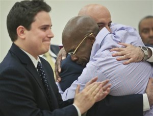 Jonathan Fleming, hugs his attorney Anthony Mayol while his other attorney Taylor Koss applaud in Brooklyn's Supreme court, after a judge declared him a free man on Tuesday April 8, 2014 in New York. Fleming, who spent almost a quarter-century behind bars for murder, was cleared of a killing that happened when he was 1,100 miles away on a Disney World vacation in 1989. (AP Photo/Bebeto Matthews)