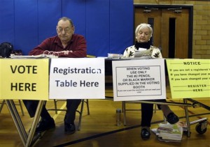 Poll workers Charles Kierstyn, left, and Bobbi Ortwein, right, wait for voters to register at their desk on Tuesday, April 1, 2014, in the gym at the Tyler-Domer Community Center in Racine,Wis. (AP Photo/The Journal Times, Scott Anderson)