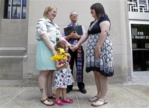 Natalie, left, and Heather Starr, with their daughter Libby, say their vows in front of Rev. Roger Bertschausen on the steps of the Outagamie County administration building on Monday, June 9, 2014 in Appleton, Wis. They are the first same sex couple to be married in the county. (AP Photo/The Post-Crescent, Wm.Glasheen)