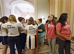 Women activists representing the National Women's Law Center, left, and Planned Parenthood, right, stand outside the Senate chamber after Senate Democrats' effort to proceed on the “Protect Women’s Health From Corporate Interference Act,” was thwarted, on Capitol Hill in Washington, Wednesday, July 16, 2014. Democrats sponsored the election-year bill to reverse last month's Supreme Court ruling that closely held businesses with religious objections could deny coverage under President Barack Obama's health care law. (AP Photo/J. Scott Applewhite)