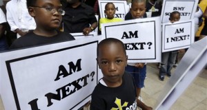 In this July 20, 2014 file photo, Alvin Duplessis, 10, left, and Thomas McGriff, 5, foreground, hold signs with others from the Watson Memorial Teaching Ministries Church of New Orleans, at a rally in New Orleans held after the acquittal of George Zimmerman. The Rev. Al Sharpton's National Action Network organized "Justice for Trayvon" rallies nationwide to press for federal civil rights charges against Zimmerman, who was found not guilty in the shooting death of the unarmed black teenager, Trayvon Martin. (AP Photo/Gerald Herbert, File)