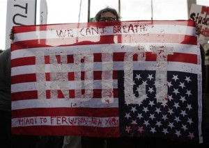 A protester holds an American flag with the word "Indict", during a protest Friday, Dec. 5, 2014, in Miami. A grand jury recently decided not to indict former police officer Darren Wilson in the shooting of Michael Brown in Ferguson, Mo. People are protesting nationwide against recent decisions not to prosecute white police officers involved in the killing of black men. (AP Photo/Lynne Sladky)