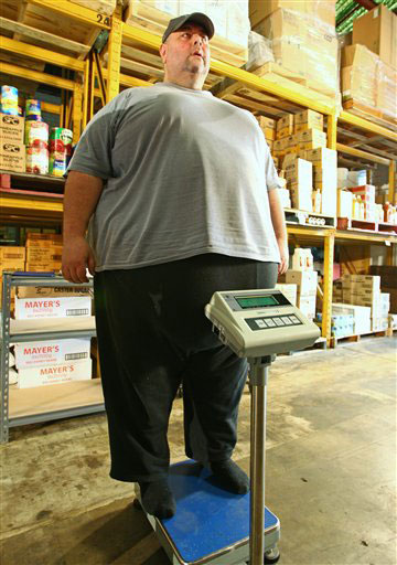 Jordan Tarekidis stands on a scale at his family's wholesale food warehouse where it shows Tarekidis weighs more than 300 kg (661 lbs) Monday, March 19, 2012, in Sydney. Tarekidis, one of Australia's most overweight men, is attempting to loose 200 kg (440 lbs) in 18 months with the help of a hypnosis expert. (AP Photo/Rick Rycroft)