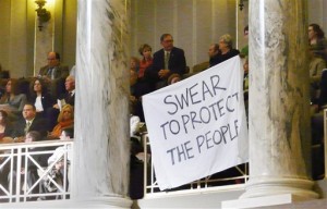 people protesting the fatal shooting of unarmed, black 18-year-old Michael Brown by a white police officer wave a banner from the Senate gallery during the opening of the Missouri legislature in Jefferson City, Mo. Police killings of unarmed residents in Missouri, New York and elsewhere have prompted an array of proposals from newly-convening state legislatures seeking to place greater scrutiny on the interactions between law officers and the public. (AP Photo/Jefferson City News Tribune, Bob Watson, File)