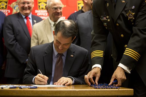 Gov. Scott Walker signs a gun bill at the Milwaukee County Sheriff's office that eliminates a 48-hour waiting period for handgun purchases, Wednesday, June. 24, 2015, in Milwaukee. (AP Photo/Jeffrey Phelps)