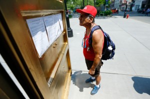 Joe Martinez reads over information about a container outfitted with video conference electronics that is part of an art installation at Military Park in downtown Newark, N.J. The portal allows people inside a container to communicate to people in containers in other cities across the world. (AP Photo/Julio Cortez)