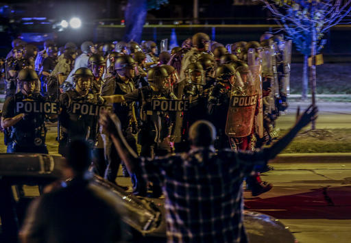 Police move in on a group of protesters throwing rocks at them in Milwaukee, Sunday, Aug. 14, 2016. Police said one person was shot at a Milwaukee protest on Sunday evening and officers used an armored vehicle to retrieve the injured victim during a second night of unrest over the police shooting of a black man, but there was no repeat of widespread destruction of property. (AP Photo/Jeffrey Phelps)