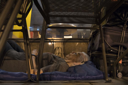 In this Aug. 10, 2016 photo, with suitcases in arms reach, homeless woman Wanda Witter beds down in her sleeping spot outside the Au Bon Pain on 13th and G Street in Washington, DC Witter, who is 80 years old, was recently attacked at the location suffering a black eye and two stitches. For 20 years she's carried suitcases full of paperwork that she says proves that Social Security owes her $93,000. A lawyer is working with her to get her money back. (Linda Davidson/The Washington Post via AP)