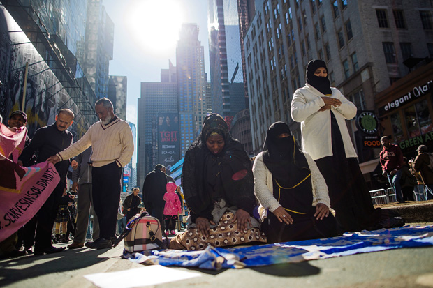 Women pray on Sunday during a protest of President Donald Trump's immigration policies in Times Square in New York City. AP PHOTO/ANDRES KUDACKI 