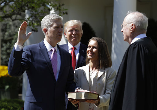 President Donald Trump watches as Supreme Court Justice Anthony Kennedy administers the judicial oath to Judge Neil Gorsuch during a re-enactment in the Rose Garden of the White House White House in Washington, Monday, April 10, 2017. Holding the bible is Gorsuch's wife Marie Louise Gorsuch. (AP Photo/Evan Vucci)