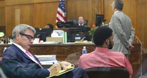 Dominique Heaggan-Brown, right, and his attorney Jonathan C. Smith, left, watch the power point presentation of use of force expert, Robert C. Willis on a video screen during the trial of former Milwaukee officer Heaggan-Brown  Monday, June 19, 2017,  in Milwaukee. A police expert in the use of deadly force says on Monday that Heaggan-Brown, on trial for fatally shooting a black man after a foot chase "acted in accordance with his training." Attorney Steven R. Kohn is at upper right. (Michael Sears/Milwaukee Journal-Sentinel via AP, Pool)
