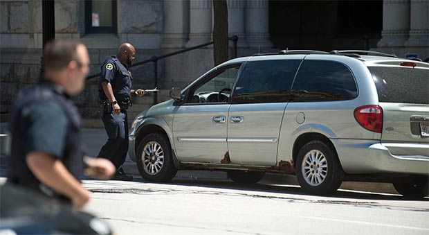 Officers with the City of Milwaukee Police Department look over a van parked in front of the United States Federal Building and Courthouse 517 East Wisconsin Avenue in Milwaukee. The van was left in front of the courthouse by a 32-year-old man who was arrested after running into the federal courthouse and made threats Thursday afternoon. (Staff photo by Kevin Harnack)