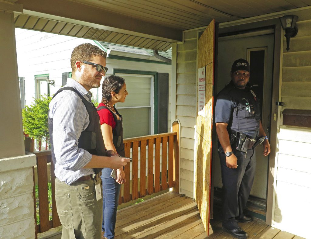 In this May 18, 2017 photo, Milwaukee prosecutor Jeremy Arn, left, Safe & Sound coordinator Claudia Pizano, center, and police officer Chauncey Harris prepare to enter a vacant home on the city's north side after neighbors expressed concern about possible criminal activity. Arn is stationed with officers in Police District 5 as part of an initiative to place prosecutors in neighborhoods. (AP Photo/Ivan Moreno)