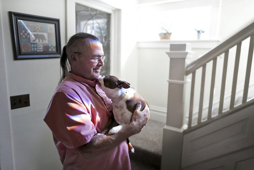 Billy Bob Grahn, founder and director of the Red Road House, holds Miss Ella near the staircase of their home in Janesville, Wis., on Wednesday, Sept. 13, 2017.  (Anthony Wahl/The Janesville Gazette via AP)