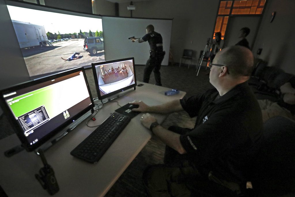 Fox Valley Technical College Law Enforcement 720 Academy director Tim Hufschmid, right, runs a training scenario for academy student Bryce LaLuzerne on Nov. 1, 2017, Fox Valley Technical College Public Safety Training Center in Greenville, Wis.   The three screens laid out in a wide semi-circle are an upgrade from a one-screen system the college previously used. When it's integrated into classes next semester, it will give students a more immersive, realistic experience when it comes to situations they'll encounter, including use-of-force — an issue that continues to draw close scrutiny across the nation.   (Wm. Glasheen /The Post-Crescent via AP)