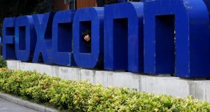 FILE - In this Thursday, May 27, 2010, file photo, a worker looks out through the logo at the entrance of the Foxconn complex in the southern Chinese city of Shenzhen. As the buzz increases over an expected imminent announcement that Wisconsin may land a massive new Foxconn manufacturing plant, concerns are also rising about what the state may have to offer up to seal the deal. (AP Photo/Kin Cheung, File)