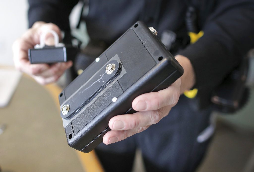 Rock County sheriff's Deputy Brian Hanthorn shows the Band-It, a device that can deliver electric shocks when fastened to the leg of inmates during jury trials. The devices are capable of delivering 50,000 volts but have never been used to shock an inmate in Rock County, officials said. (Anthony Wahl/The Janesville Gazette via AP)
