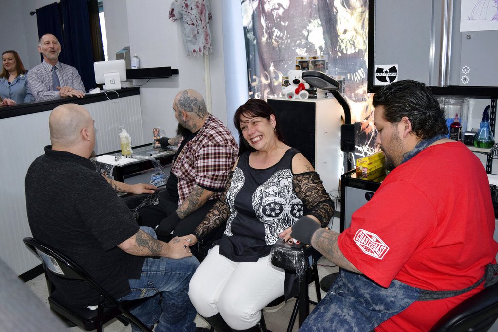 In this April 20, 2018 photo, from left, groom Rich Ziemer, tattoo artist Gabriel Rocha, bride Amber Ziemer and House of Lexx Tattoo and Piercings owner and tattoo artist Alex Valadez gather for a wedding in Beloit, Wis. Officiant Steve Meyer, above left, married the Ziemers at the tattoo shop. Although Meyer said he had officiated more than 4,000 weddings, it was his first ceremony in a tattoo shop. (Hillary Gavan/The Beloit Daily News via AP)