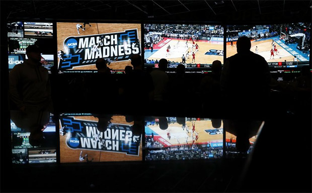 In this March 15, 2018 photo, people watch coverage of the first round of the NCAA college basketball tournament at the Westgate Superbook sports book in Las Vegas. The Supreme Court has struck down a federal law that bars gambling on football, basketball, baseball and other sports in most states, giving states the go-ahead to legalize betting on sports. (AP Photo/John Locher)