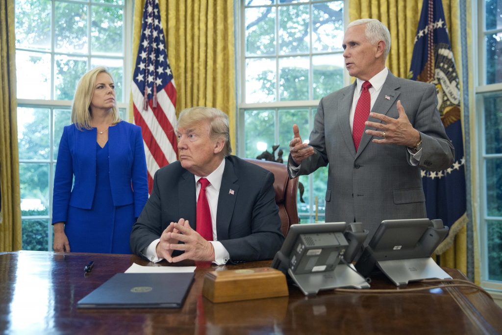 President Donald Trump, center, and Vice President Mike Pence, right, address members of the media before signing an executive order to end family separations at the border, during an event in the Oval Office of the White House in Washington, Wednesday. Looking on is Homeland Security Secretary Kirstjen Nielsen, left. (AP Photo/Pablo Martinez Monsivais)