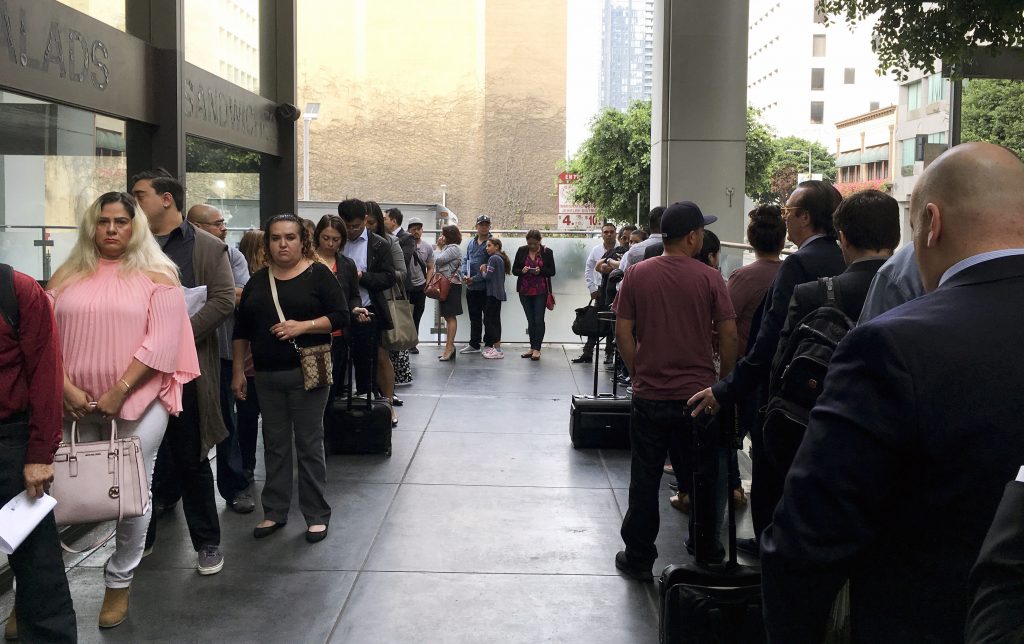 FILE - In this June 19, 2018, file photo, immigrants awaiting deportation hearings line up outside the building that houses the immigration courts in Los Angeles. In recent weeks, immigration judges have been thrust into the center of the heated political controversy over how the Trump administration is handling the cases of mostly Central American immigrants caught on southwest border. (AP Photo/Amy Taxin, File)