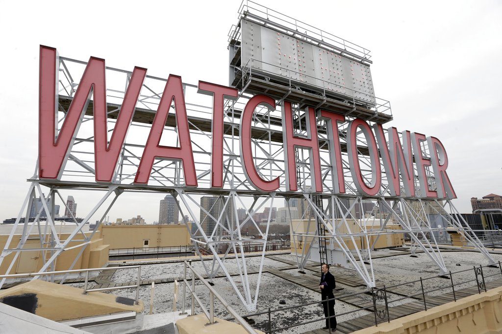 File - In this Wednesday, Dec. 9, 2015, file photo, the iconic Watchtower sign is seen on the roof of 25-30 Columbia Heights, then world headquarters of the Jehovah's Witnesses, in the Brooklyn borough of New York. Two women who were sexually abused as children say the Jehovah's Witnesses failed to report their abuser to authorities in Montana, and instead expelled him from the congregation as punishment until he repented. The Thompson Falls trial that begins Monday, Sept. 24, 2018, is one of dozens of lawsuits filed nationwide over the last decade alleging mismanagement of sexual abuse claims by Jehovah's Witness clergy and members. (AP Photo/Seth Wenig)