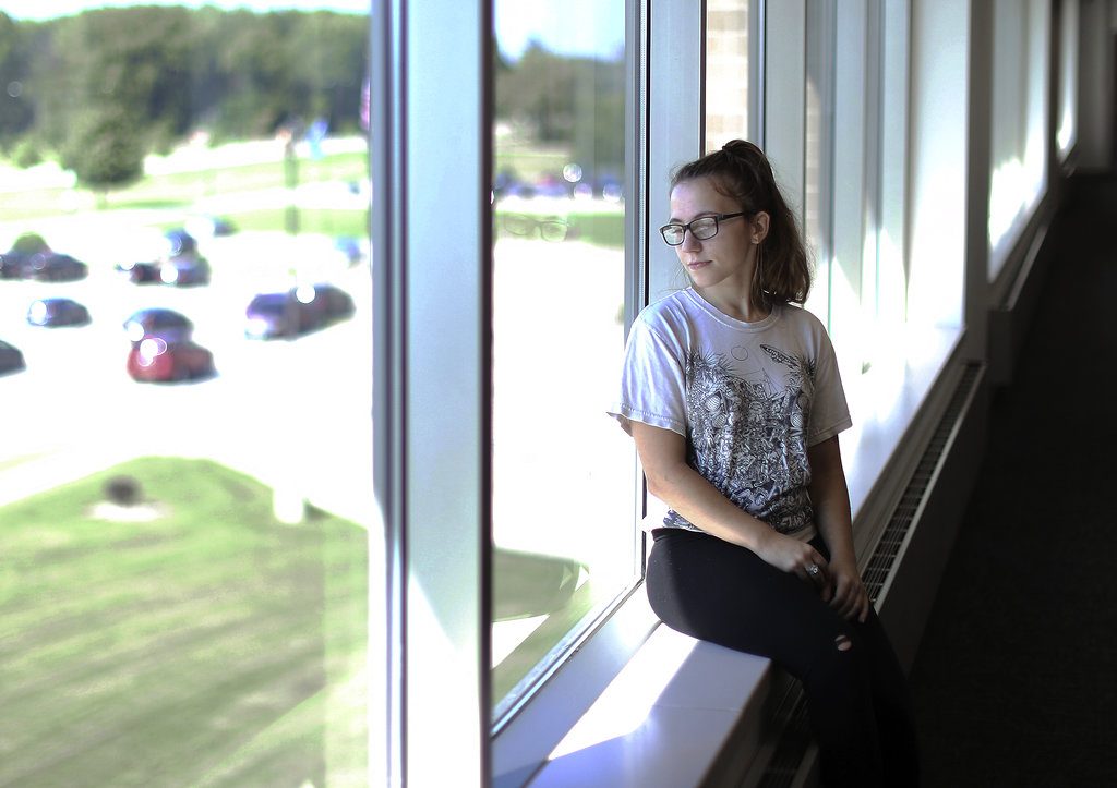 Hailey Beles looks outside while seated on the window sill moments before attending Walworth County Drug Court in Elkhorn, Wis. (Anthony Wahl/The Janesville Gazette via AP)