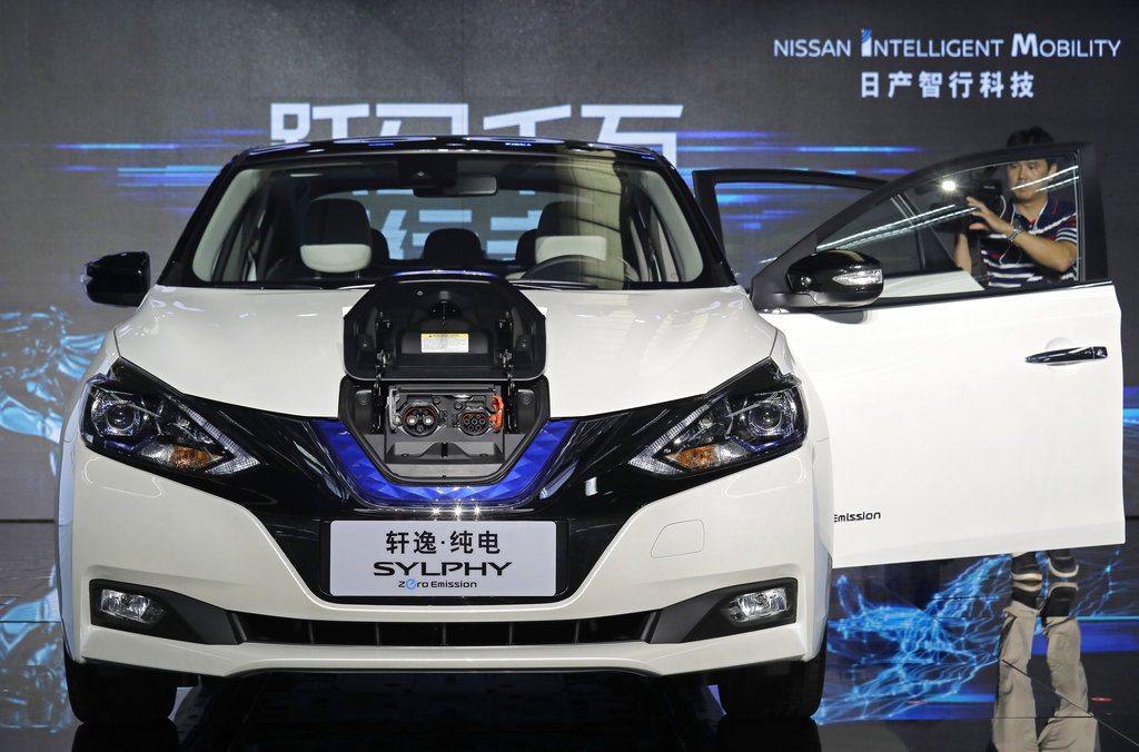 FILE - In this Aug. 27, 2018, file photo, a cameraman takes video of a Nissan Sylphy Zero Emission, the Nissan's first all-electric vehicle built in China, at the Nissan factory in Guangzhou, Guangdong province, China. More than 200 manufacturers, including Tesla, Volkswagen, BMW, Daimler, Ford, General Motors, Nissan, Mitsubishi and U.S.-listed electric vehicle start-up NIO, transmit position information and dozens of other data points to government-backed monitoring centers, The Associated Press has found. Generally, it happens without car owners' knowledge. (AP Photo/Vincent Yu, File)