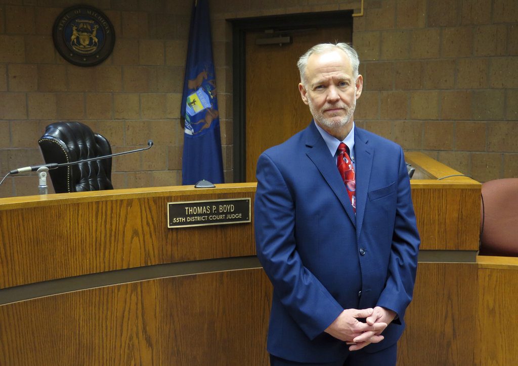In this Wednesday, Nov. 14, 2018, photo, Ingham County District Court Judge Thomas Boyd poses for a photo in his courtroom in Mason, Mich. Boyd says it's a conflict for judges to order a criminal defendant to pay for the operations of a local court. The Michigan Supreme Court is hearing arguments Monday, Nov. 19 in a case that will determine if it's an illegal tax. (AP Photo/David Eggert)