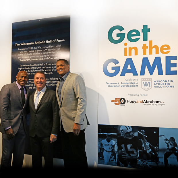 Hupy and Abraham Managing Partner Jason Abraham (center) stands alongside Donald Driver (left) and Marques Johnson in front of the “Get in the Game” exhibit at the Discovery World in Milwaukee. The firm is sponsoring the exhibit as part of its 50th anniversary celebration. (Photo submitted by Hupy and Abraham)