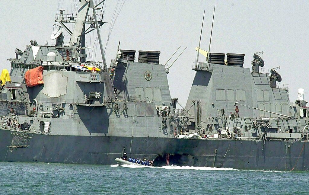 FILE - In this Oct. 15, 2000 file photo, experts in a speed boat examine the damaged hull of the USS Cole at the Yemeni port of Aden after an al-Qaida attack that killed 17 sailors. The Supreme Court on Tuesday threw out a nearly $315 million judgment against Sudan stemming from the USS Cole bombing, saying Sudan hadn’t properly been notified of the lawsuit. (AP Photo/Dimitri Messinis, File)