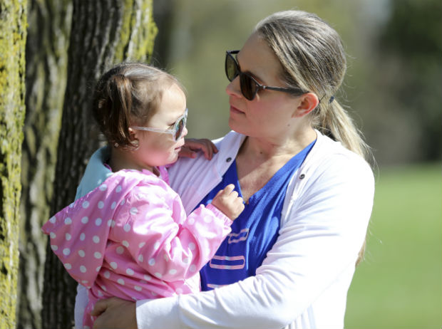 Lisa Kum holds her daughter, Emma, in a park near Madison on April 23. In 2014, Kum's husband, Sothy Kum, allowed an acquaintance to pay him to send marijuana to his house. He was convicted of the possession of marijuana with the intent to deliver and served a year in prison. He was later detained by Immigration and Customs Enforcement and deported in April 2018. Sothy Kum is a Cambodian refugee who left the country as a child. He is among the thousands of immigrants who are deported each year for marijuana-related charges. (Coburn Dukehart/Wisconsin Watch via AP)