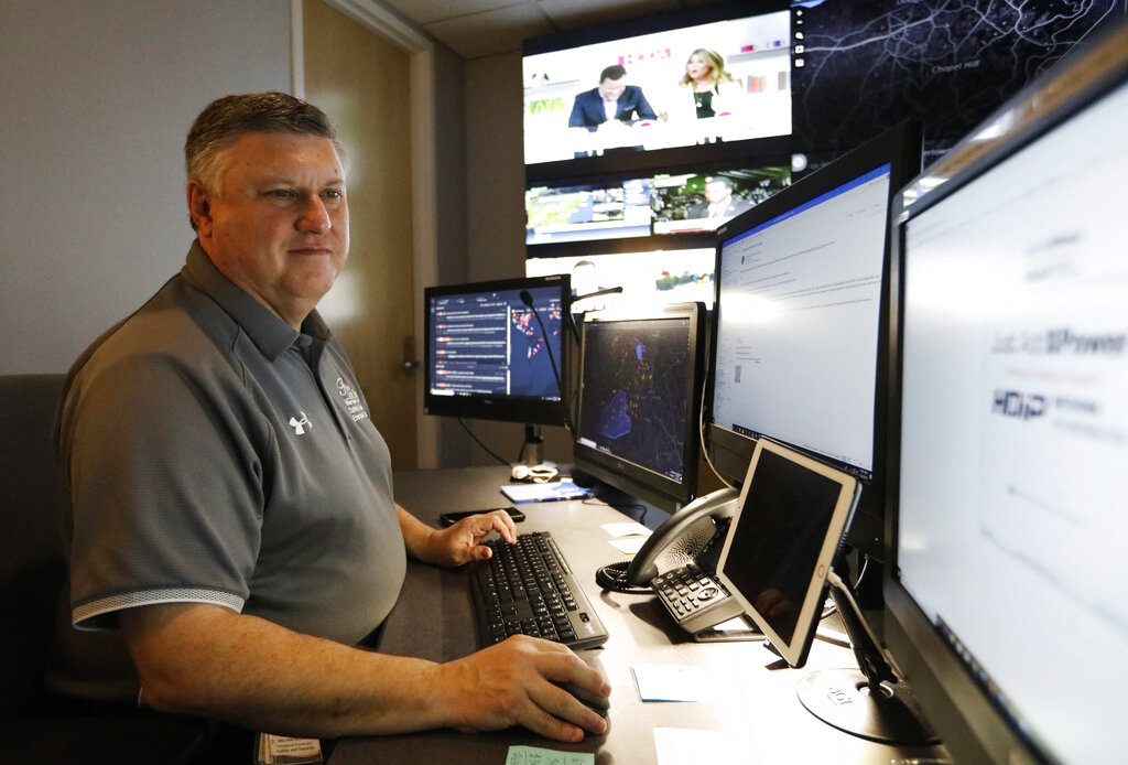 In this July 30, 2019, photo, Paul Hildreth, emergency operations coordinator for the Fulton County School District, works in the emergency operations center at the Fulton County School District Administration Center in Atlanta. Artificial Intelligence is transforming surveillance cameras from passive sentries into active observers that can immediately spot a gunman, alert retailers when someone is shoplifting and help police quickly find suspects. Schools, such as the Fulton County School District, are among the most enthusiastic adopters of the technology. (AP Photo/Cody Jackson)