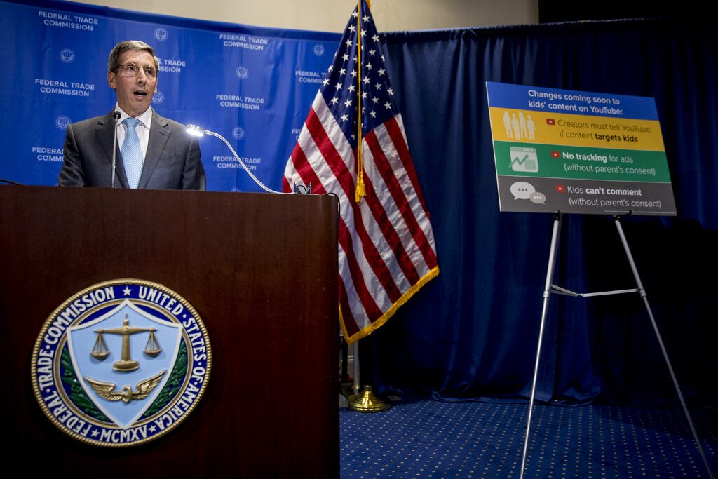 A sign with coming changes to kids' comment on YouTube is displayed as Federal Trade Commission Chairman Joe Simons speaks at a news conference at the Federal Trade Commission in Washington, Wednesday, Sept. 4, 2019, to announce that Google's video site YouTube has been fined $170 million to settle allegations it collected children's personal data without their parents' consent. (AP Photo/Andrew Harnik)