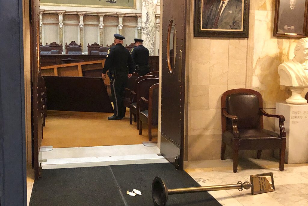 Wisconsin Capitol Police survey damage inside the state Supreme Court chamber in the Capitol after the man apparently toppled an ornate table on Tuesday, Nov. 26, 2019, in Madison, Wis. The court chamber was open to the public, but the Supreme Court was not present at the time of the incident. (AP Photo/Scott Bauer)