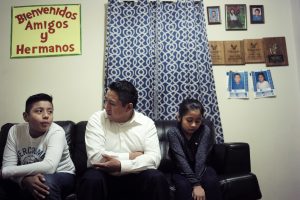 Audencio Lopez, center, who crossed the border illegally as a teenager in 1997, is seated with two of his children, Anaias, 12, left, and Mercy, 8, right, during an interview with The Associated Press at their house in Lynn, Massachusetts on Nov. 21. (AP Photo/Steven Senne
