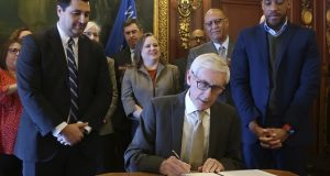 Gov. Tony Evers signs an executive order on Monday setting up what he promises will be a nonpartisan redistricting commission. Evers signed the order in his Capitol office, surrounded by Democratic office holders, members of his administration and supporters of redistricting reform. Republicans have dismissed the attempt as a sham. (AP Photo by Scott Bauer)