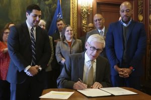 Gov. Tony Evers signs an executive order on Monday setting up what he promises will be a nonpartisan redistricting commission. Evers signed the order in his Capitol office, surrounded by Democratic office holders, members of his administration and supporters of redistricting reform. Republicans have dismissed the attempt as a sham. (AP Photo by Scott Bauer)