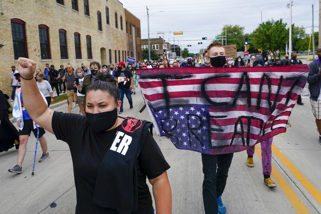 A protester holds a flag during a Black Lives Matter march Tuesday, Sept. 1, 2020, in Kenosha, Wis. (AP Photo/Morry Gash)