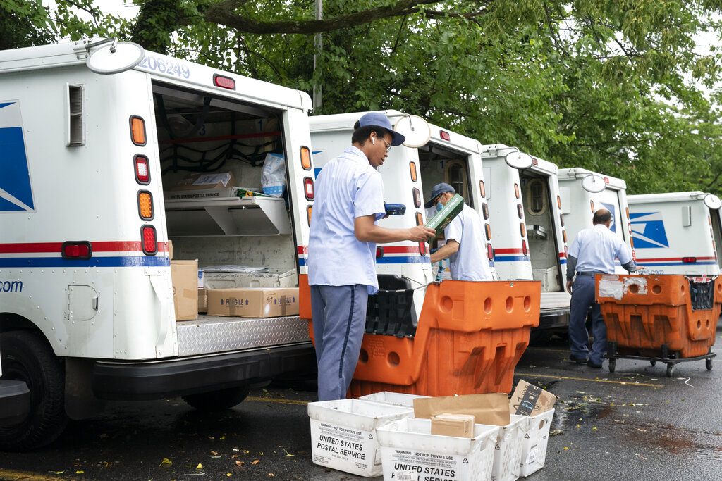 FILE - In this July 31, 2020, file photo, letter carriers load mail trucks for deliveries at a U.S. Postal Service facility in McLean, Va. A U.S. judge on Thursday, Sept. 17, 2020, blocked controversial Postal Service changes that have slowed mail nationwide. The judge called them "a politically motivated attack on the efficiency of the Postal Service" before the November election. (AP Photo/J. Scott Applewhite, File)